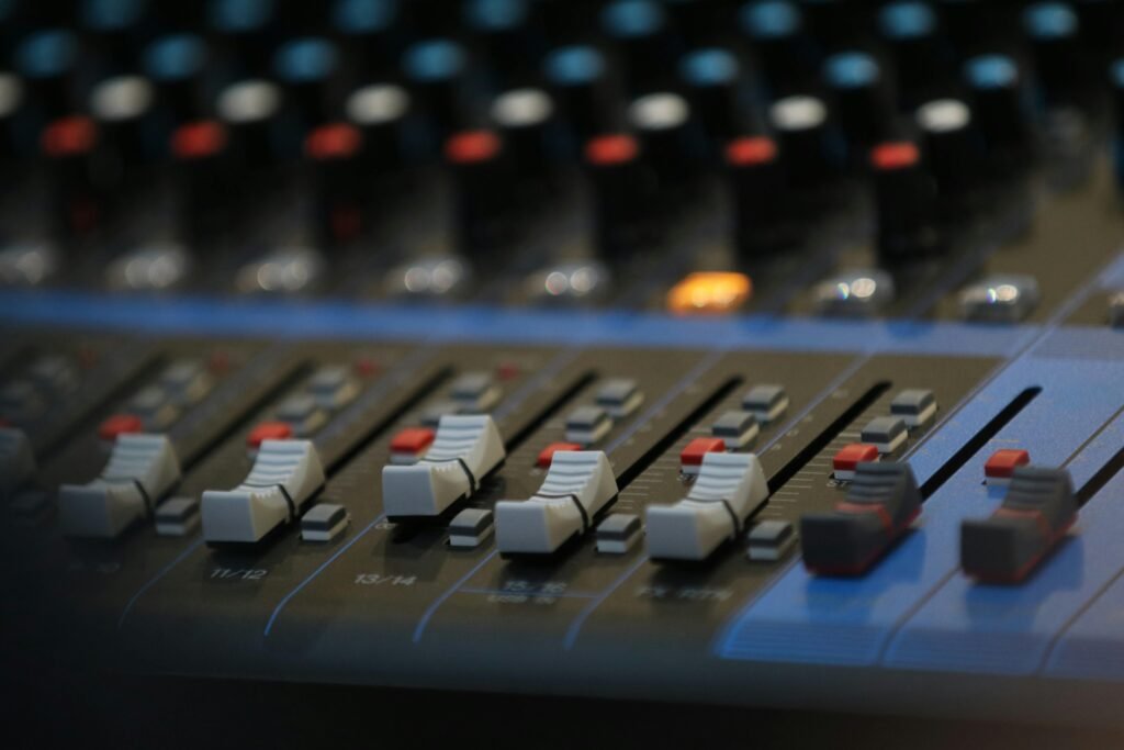 Close-up of an advanced audio mixing panel with slide controls and knobs in a studio setting.